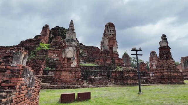ancient brick temple ruins with tiered prangs under overcast sky, ayutthaya, thailand