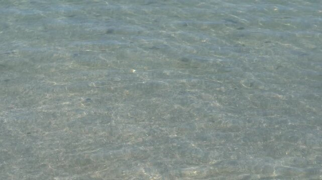 Small gentle ripples on clear shallow water over sand, natural sea water background