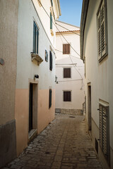 Fototapeta premium Narrow medieval stone alleyway with traditional Mediterranean architecture in the Old Town of Krk, Croatia