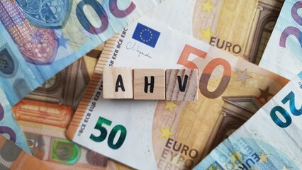 Obraz premium AHV acronym made of wooden letter cubes on pile of Euro banknotes. Allgemeine Altersversicherung (General Old-Age Insurance)