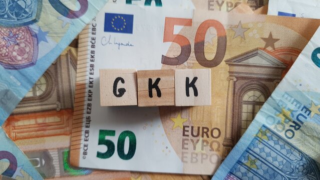GKK acronym made of wooden letter cubes on pile of Euro banknotes. Geb&auml;ude-Kostenversicherung (Building Cost Insurance)