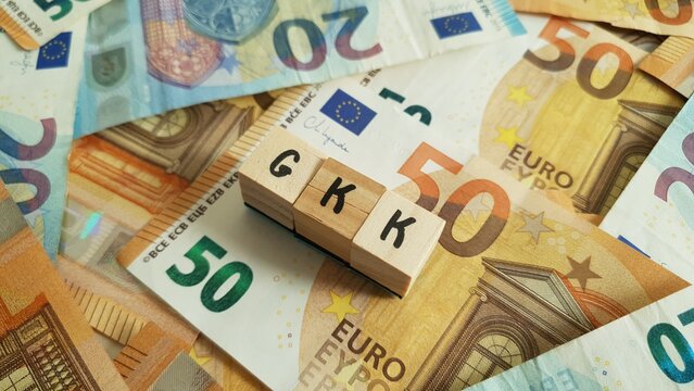 GKK acronym made of wooden letter cubes on pile of Euro banknotes. Geb&auml;ude-Kostenversicherung (Building Cost Insurance)