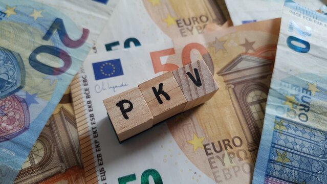 PKV acronym made of wooden letter cubes on pile of Euro banknotes. Private Krankenversicherung (Private Health Insurance)