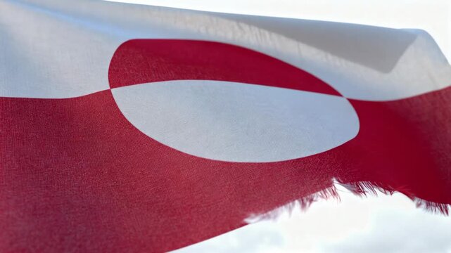 Rippling red-white flag with round emblem waving from rising breeze under bright sky, frayed fringe