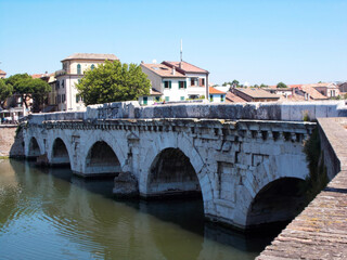 Obraz premium Historical stone bridge over a canal in Rimini, Italy on a clear sunny day