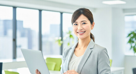 オフィスでノートPCを持つ笑顔の女性社員