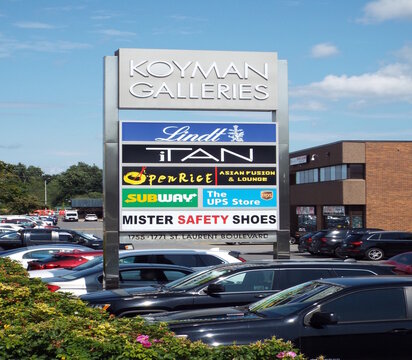 Ottawa, ON, Canada-July 11,2025: A multi-tenant pylon sign at 1755-1771 St. Laurent Blvd displays logos for "Koyman Galleries, Lindt, iTAN, OpenRice, Subway, and UPS."
