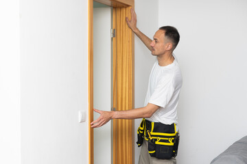 Professional handyman checks vertical alignment of interior door during installation. Home repair and renovation