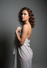 Naklejka premium Elegant Studio Portrait of Woman in White Draped Fabric, Side Profile on Grey Background