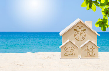 Wooden house model with environmental logo on tropical beach, clean energy, environmental friendly, global warming, green technology