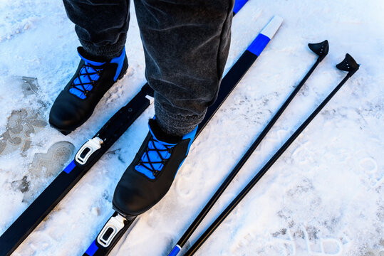 Putting on skis, preparing for ride in winter snowy nature. Attaching cross country skis to ski boots.
