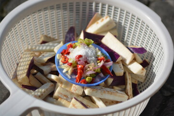Eggplant slices in colander with chili salt seasoning bowl preparation