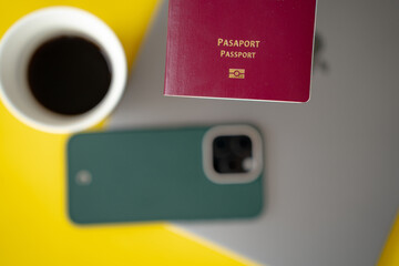A burgundy Turkish Republic passport is pictured in front of a laptop, phone, and coffee cup.