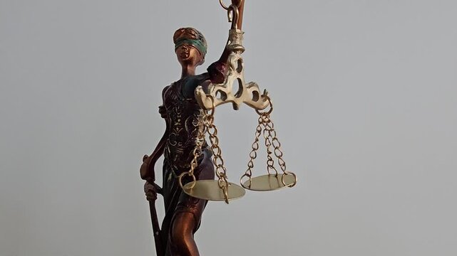 Justice statue holding scales represents fairness and law in a courtroom setting