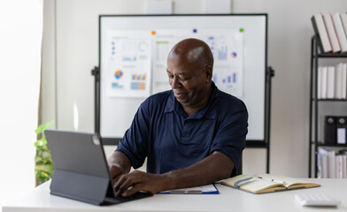 Senior businessman working with laptop and smiling in office.