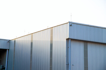 Fototapeta premium Modern industrial factory building exterior with metal corrugated wall and ventilation exhaust ducts.Minimalist silver metal warehouse facade with industrial air vents and copy space.