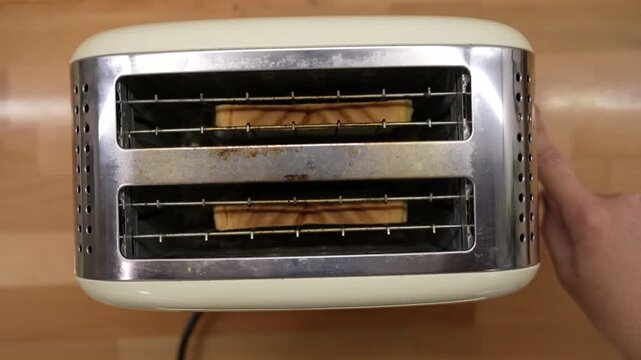 
An unrecognizable person places slices of bread in a vintage-style beige toaster and turns it on