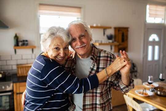 Smiling senior couple dancing in home kitchen