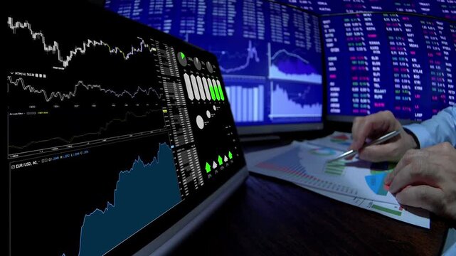 Person analyzing financial data on multiple screens