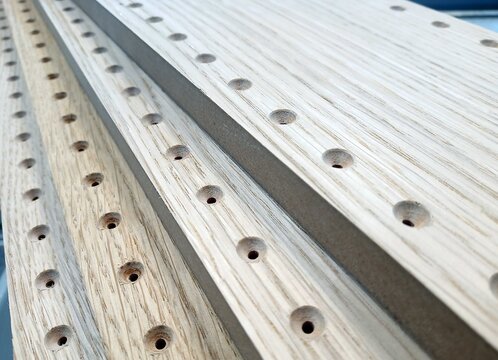drilled with countersinking for screws furniture parts covered with oak veneer. holes in the parts in a row. technological holes for fastening fittings. careful drilling.