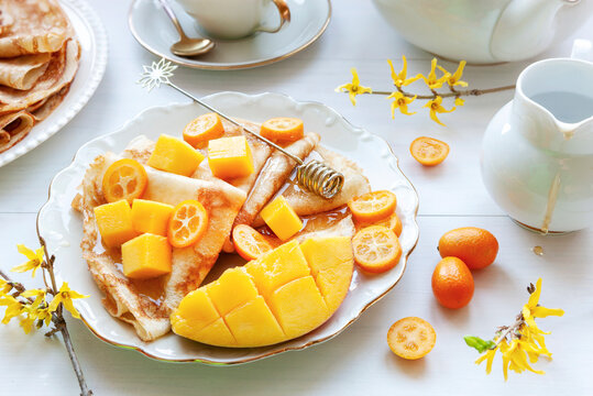 Delicious homemade pancakes with mango, kumquat and honey. Top view, close up