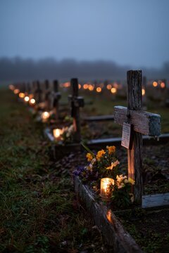 Kerzenlicht und Blumen um Holzkreuze im Gedenkbereich