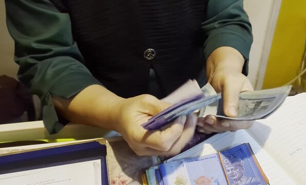 Close-up of person hands counting a stack of Malaysian Ringgit banknotes, MYR currency and financial concept