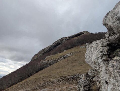 Paesaggio montano con pendii rocciosi e cielo nuvoloso, atmosfera naturale e selvaggia 
