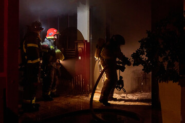 Fototapeta premium fire brigade extinguishes a burning building at night