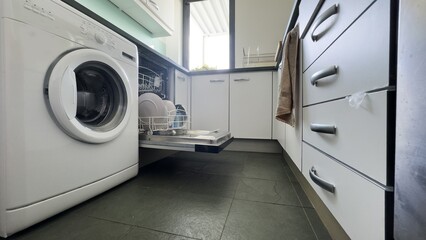 Using a dishwasher. Dishwasher basket with clean dishes inside. Modern home kitchen.