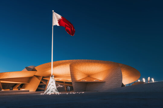 30 November 2025, Doha, Qatar: National Museum exterior at dusk, showcasing its contemporary architecture inspired by the desert rose and Qatari flag