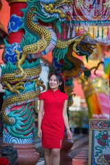 Young Woman in Traditional Red Dress Near Colorful Dragon Decorations