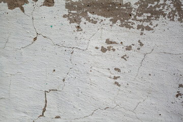Obraz premium Cracked White Wall Texture Revealing Layers of Wear in an Old Building Under Natural Light in an Urban Setting