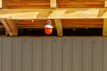 A small red signal lamp is suspended from ceiling beams, communicating caution and hazard awareness. The simple composition emphasizes workplace safety, temporary installation, and alert signage in an