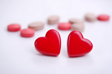 Obraz premium Red heart shapes in front of small round candies on a plain background during a festive event for love or friendship
