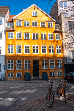 Quiet square street scene with bicycle and colorful building facade shows architecture in copenhagen denmark as spring sunlight returns