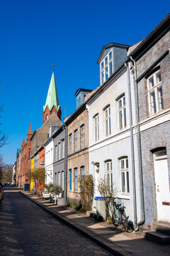 Long street perspective frames church spire beside colorful architecture facade and sky above copenhagen denmark in quiet city light