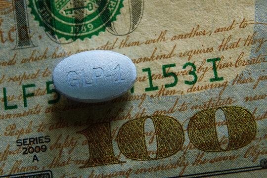 Closeup of a GLP-1 pill on a US hundred dollar bill