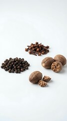 Obraz premium Assorted whole spices and nuts including black peppercorns, cloves, and walnuts arranged on white background for culinary and cooking projects.