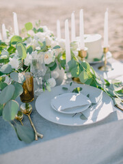 Luxury table centerpiece with candles and floral arrangement in soft sunlight, romantic event styling.