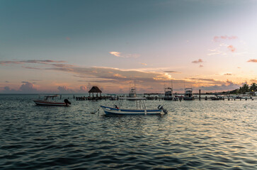Fototapeta premium Fishing boats and the pier of Puerto Morelos in Mexico at sunset