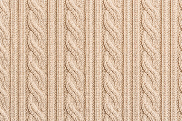 Close-up of beige cable knit fabric with classic braided pattern. Seamless knitted texture background suitable for cozy winter fashion, neutral textile design, seasonal decor