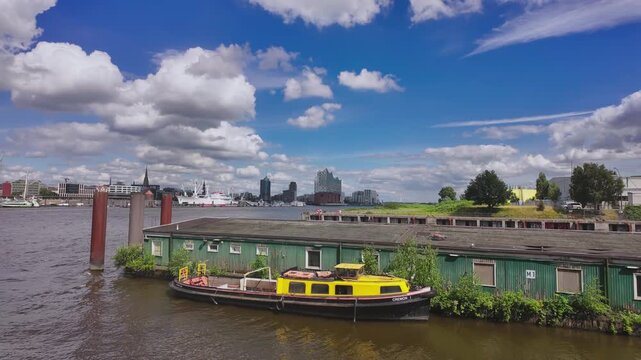 Time-lapse footage of the yellow ships at the nearby port on the Elbe River, the Hamburg port in the distance, and the Elbphilharmonie concert hall on a clear summer day.