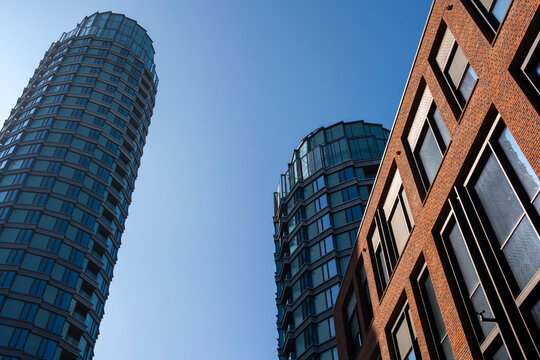 Modern urban architecture perspective looking up at glass and brick skyscraper towers in Copenhagen Denmark under clear blue sky today