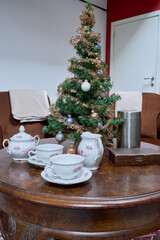 Artificial Christmas tree placed on a round living room table with a tea set