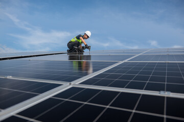 Technician installing solar panels on factory roof for green energy. A skilled technician in safety...