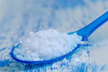 Spoon Holds White Salt on a Blue Background