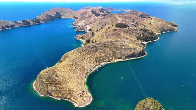 Aerial drone view of the Island of the Sun on Lake Titicaca in Bolivia. Isla del Sol in the Andes Mountains. A landscape with a small village surrounded by deep blue water.	