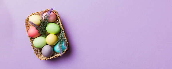 Multi colors Easter eggs in the woven basket on colored background . Pastel color Easter eggs. holiday concept with copy space