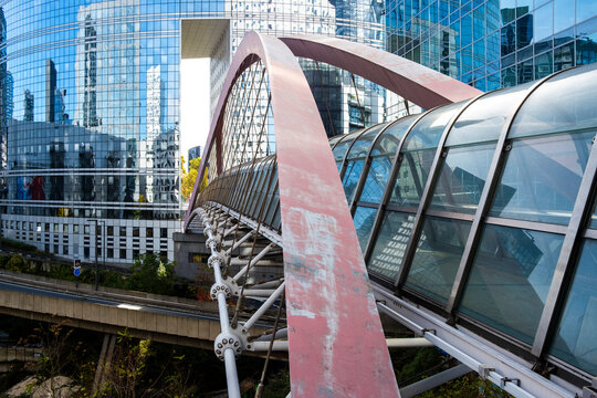Modern corporate architecture features glass bridge walkway with arch structure in Paris La Defense connecting offices across the financial district